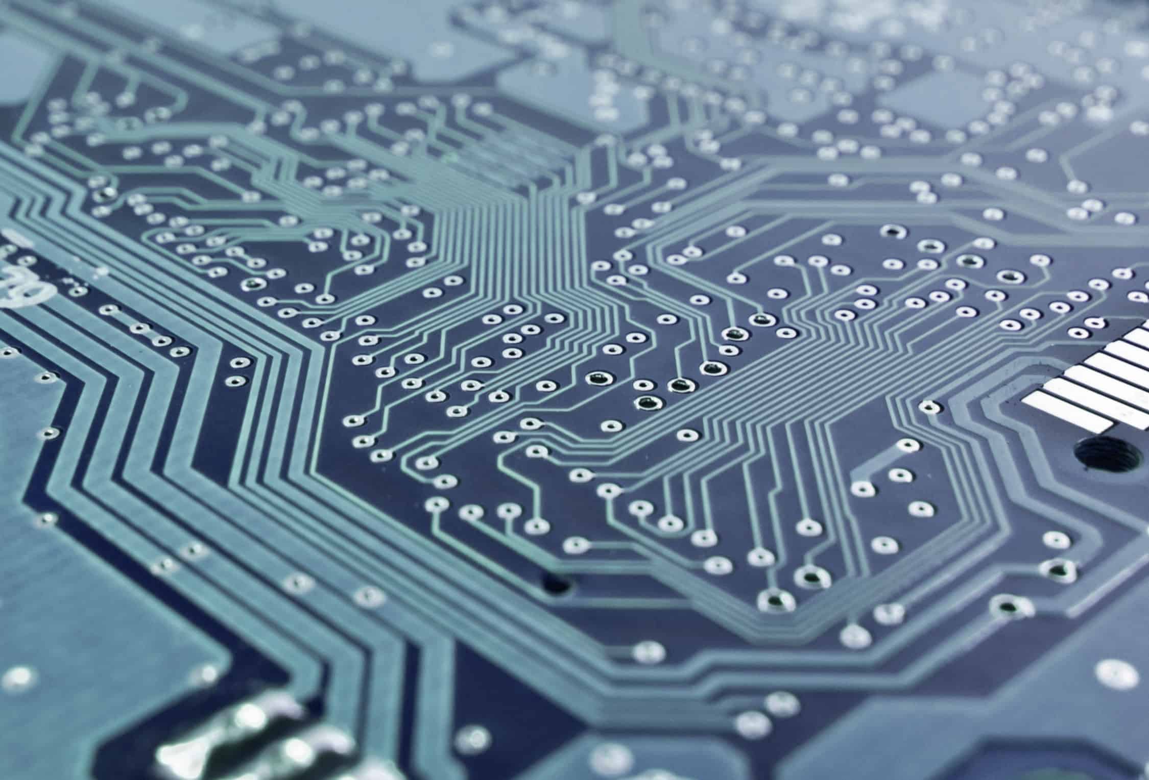 Circuit imprimé bleu avec pistes conductrices et trous de connexion pour composants électroniques.