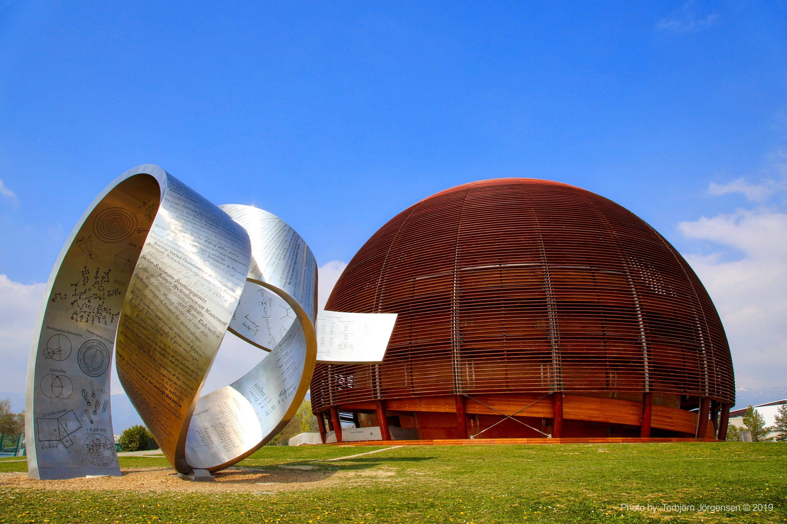 Dôme en bois à côté d'une sculpture métallique ruban de Möbius avec textes scientifiques.
